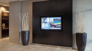 A lobby with a large digital display, two potted plants, and a modern design. - Courtyard by Marriott Richmond/Berkeley (San Pablo)