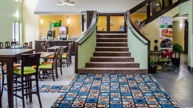 A hotel lobby with a staircase, dining area, and a kitchen in the background. - Quality Inn & Suites Medina - Akron West (Medina)