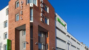 Un moderno edificio de hotel con un llamativo letrero que dice 'HOTEL', múltiples ventanas y un visible letrero de 'ibis styles'.