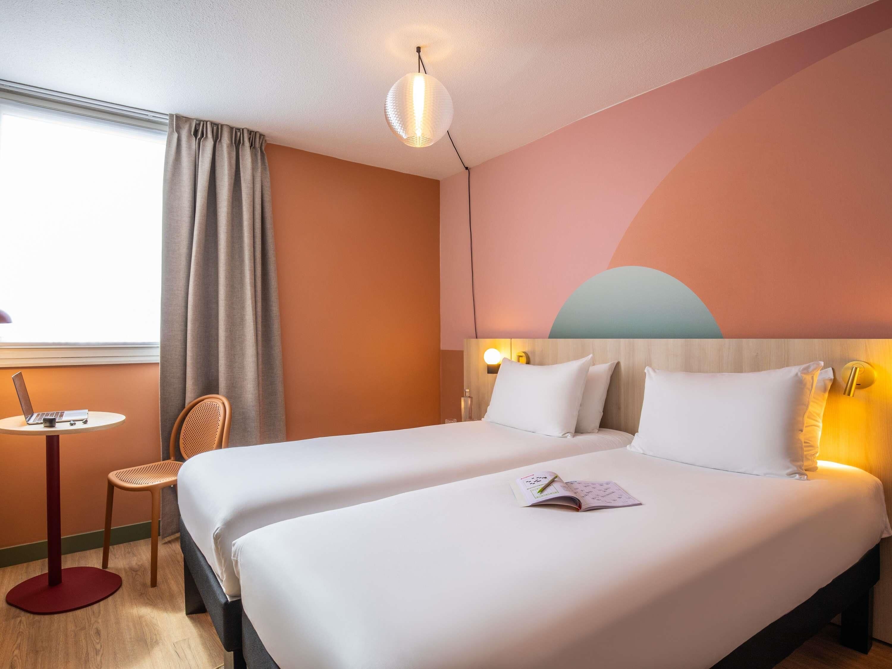 A hotel room with a bed, a desk, a chair, and a window.