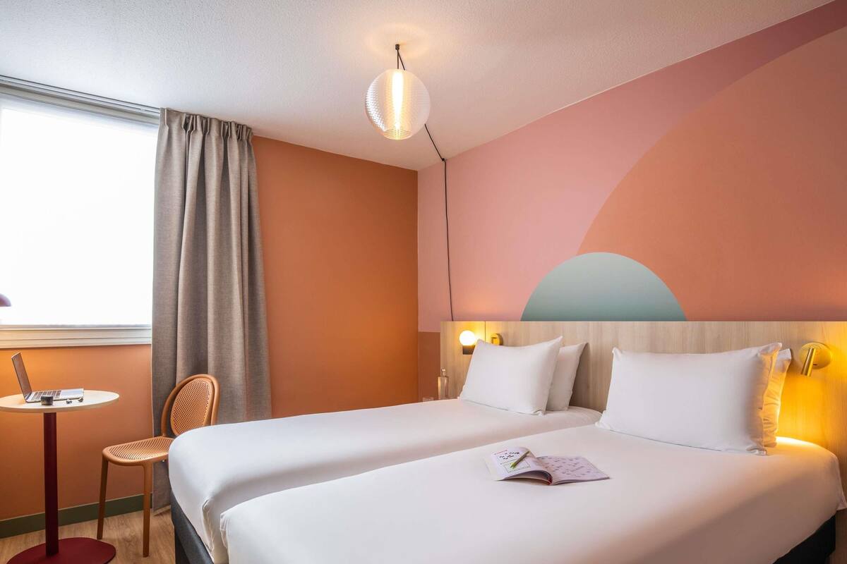 A hotel room with a bed, a desk, a chair, and a window.
