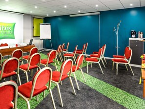 A conference room with red chairs, a projector, a whiteboard, and a green carpet. - ibis Styles Reims Centre Cathédrale (Reims)