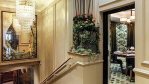 A grand staircase with a chandelier, a mirror, and a floral arrangement.