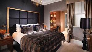 A modern bedroom with a large bed, a chandelier, a desk, and a TV.