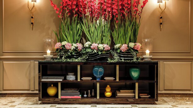 A reception area with a console table displaying flowers, candles, and decorative items.