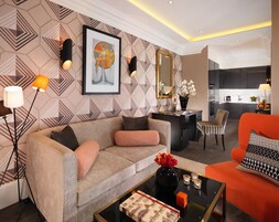 Una sala de estar moderna con un sofá, sillones, una mesa de centro y una zona de comedor con una cocina al fondo.