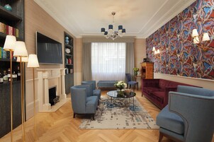 A living room with a fireplace, blue sofas, a coffee table, and a patterned wall.