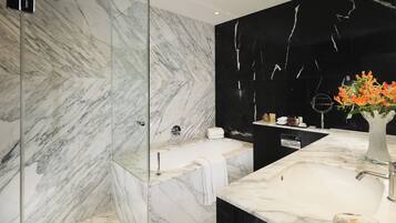 A modern bathroom with a glass-enclosed shower, a freestanding bathtub, and a marble vanity with a sink and mirror.