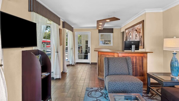 A hotel lobby with a sofa, a TV, a reception desk, and a patterned rug. - Best Western University Lodge (Davis)
