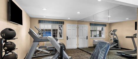 A gym with treadmills, a mirrored wall, and a weight rack.