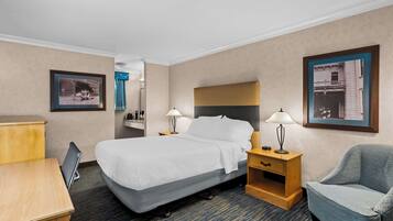 Een hotelkamer met een bed, nachtkastjes, een bureau, een stoel en foto's in lijsten aan de muur.