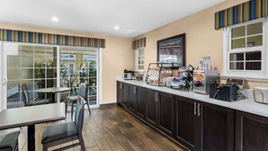 A modern kitchen with a counter, appliances, and seating area. - Best Western University Lodge (Davis)