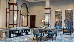 A spacious lobby with a seating area, a dining table, and a staircase.