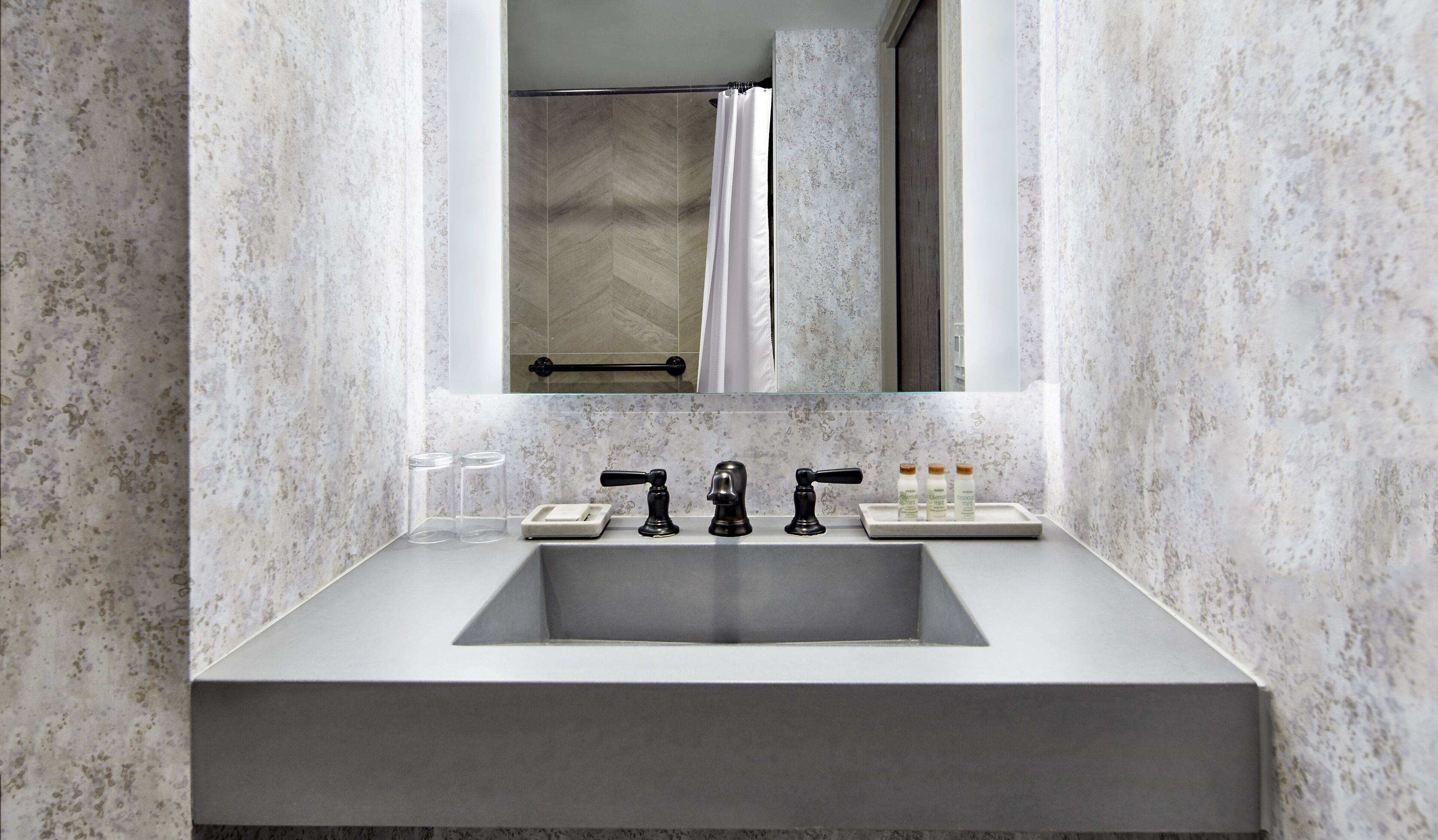 A bathroom with a large mirror, a rectangular sink, and a shower curtain.