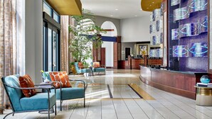 A modern lobby with a reception desk, seating area with sofas, and a large decorative wall.