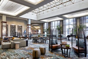 Een ruime lobby met een hoge plafond, grote ramen en modern meubilair.