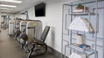 A gym with exercise machines and a wall-mounted TV.