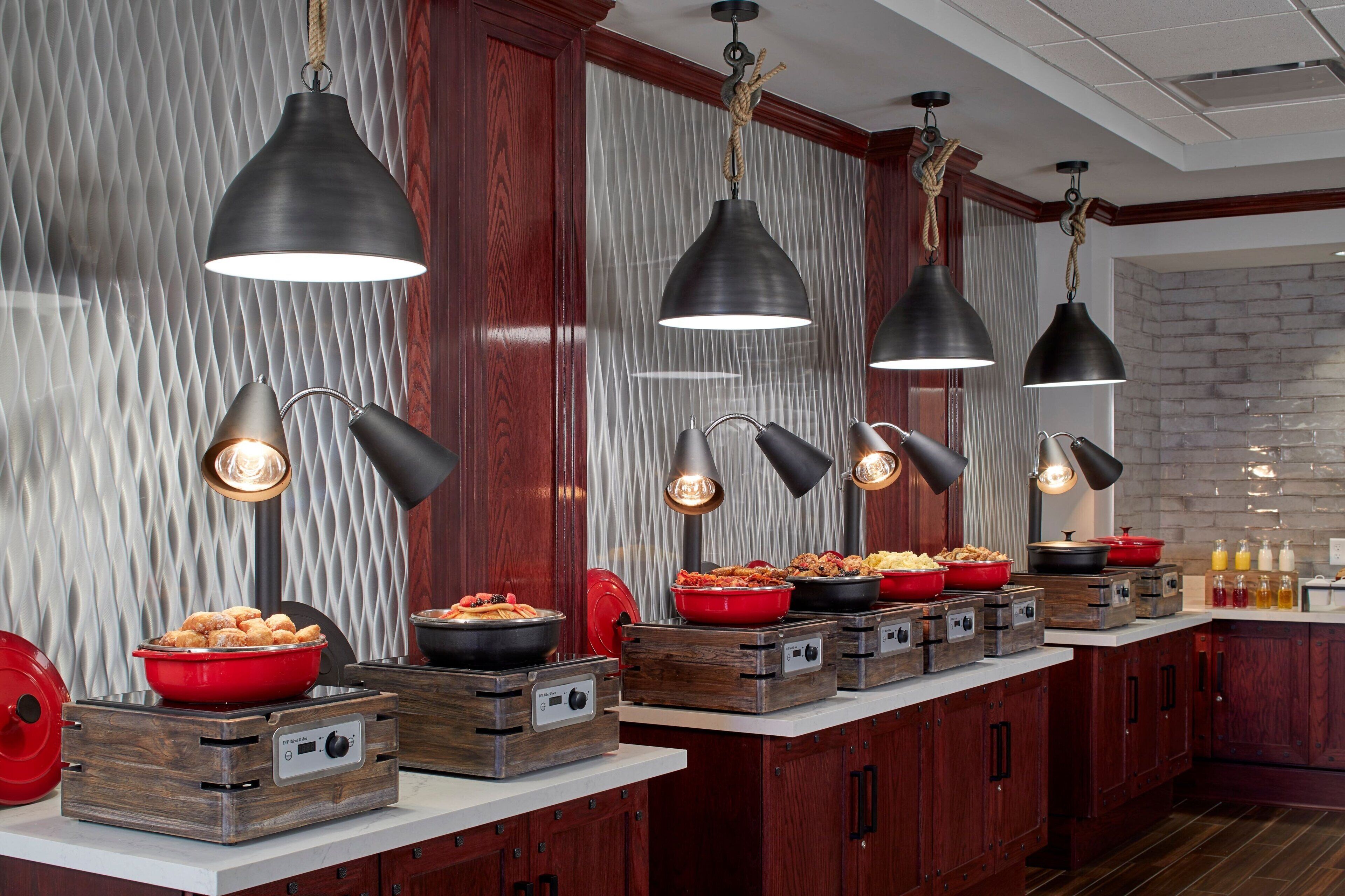 Una cocina con armarios de madera, pared de ladrillo y encimera con alimentos y recipientes.