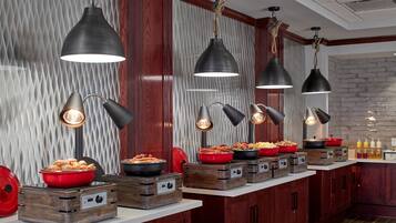 Una cocina con armarios de madera, pared de ladrillo y encimera con alimentos y recipientes.