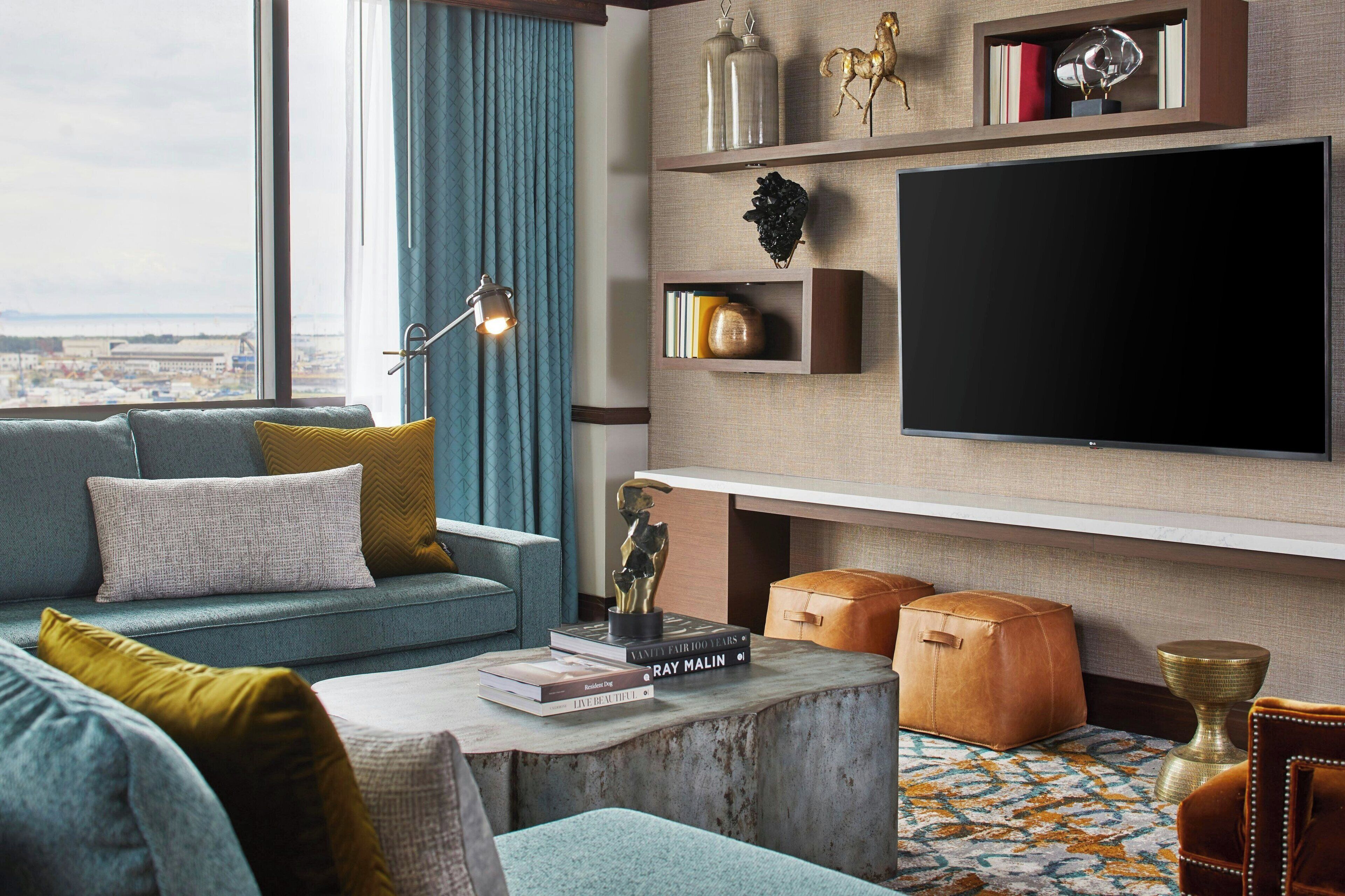 Una sala de estar moderna con un televisor grande, un sofá, una mesa de centro y vistas de la ciudad.