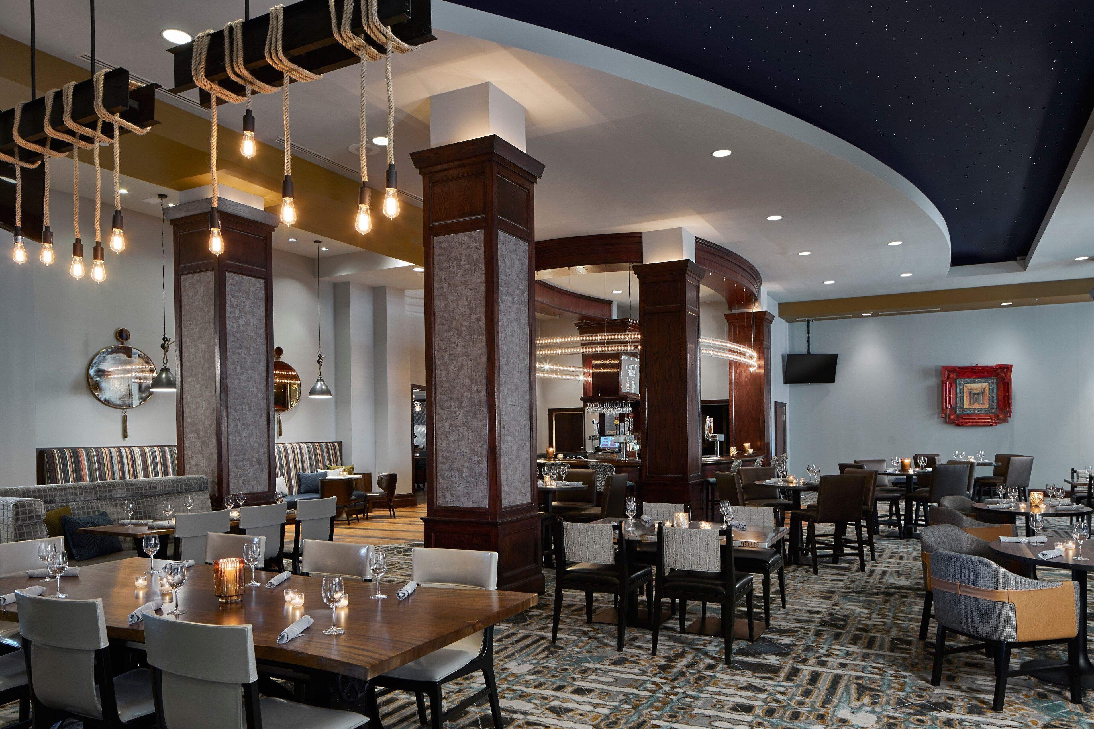 A spacious hotel lobby with a bar area, seating arrangements, and a ceiling with a starry design.