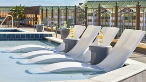 A rooftop pool area with lounge chairs and a small pool.