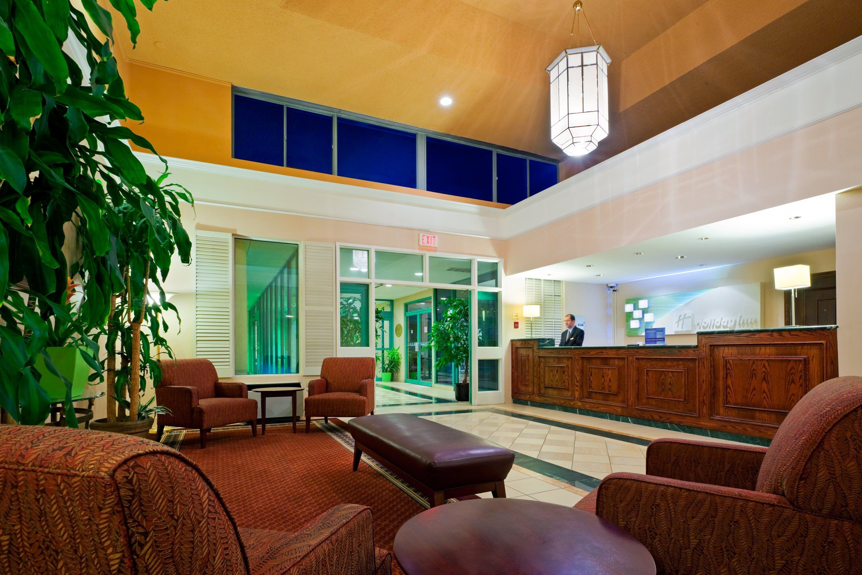A hotel lobby with a reception desk, seating area, and a large window.