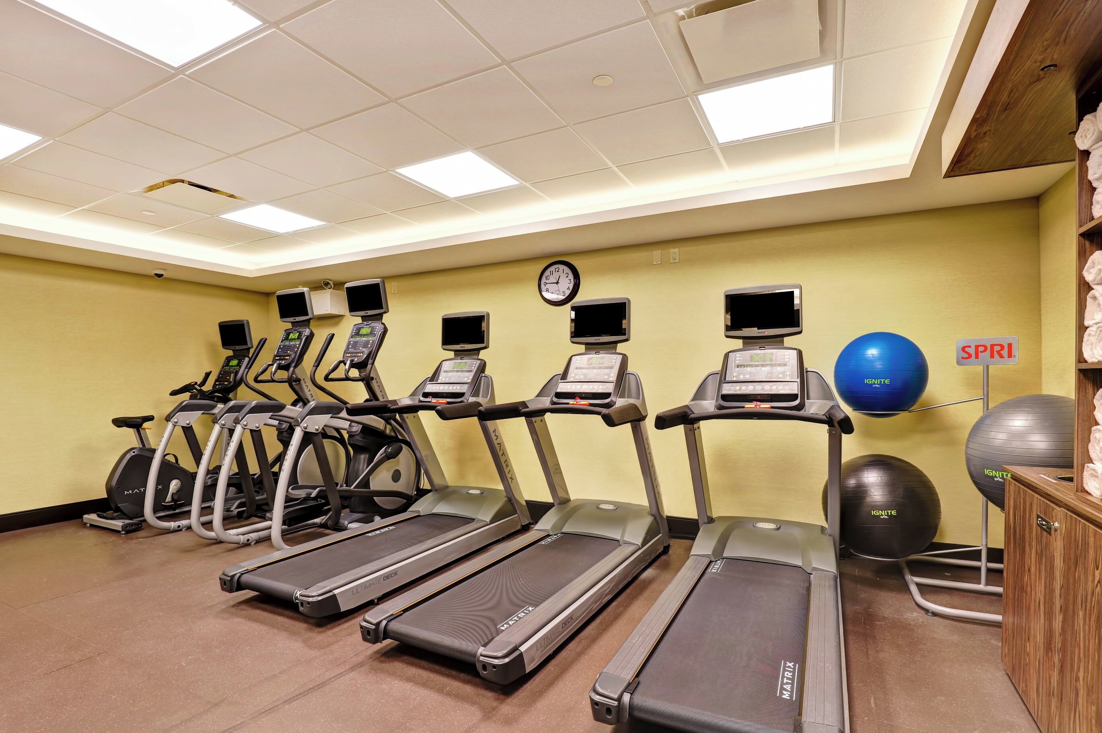 Academia com esteiras, bicicletas ergométricas e bolas de exercício.