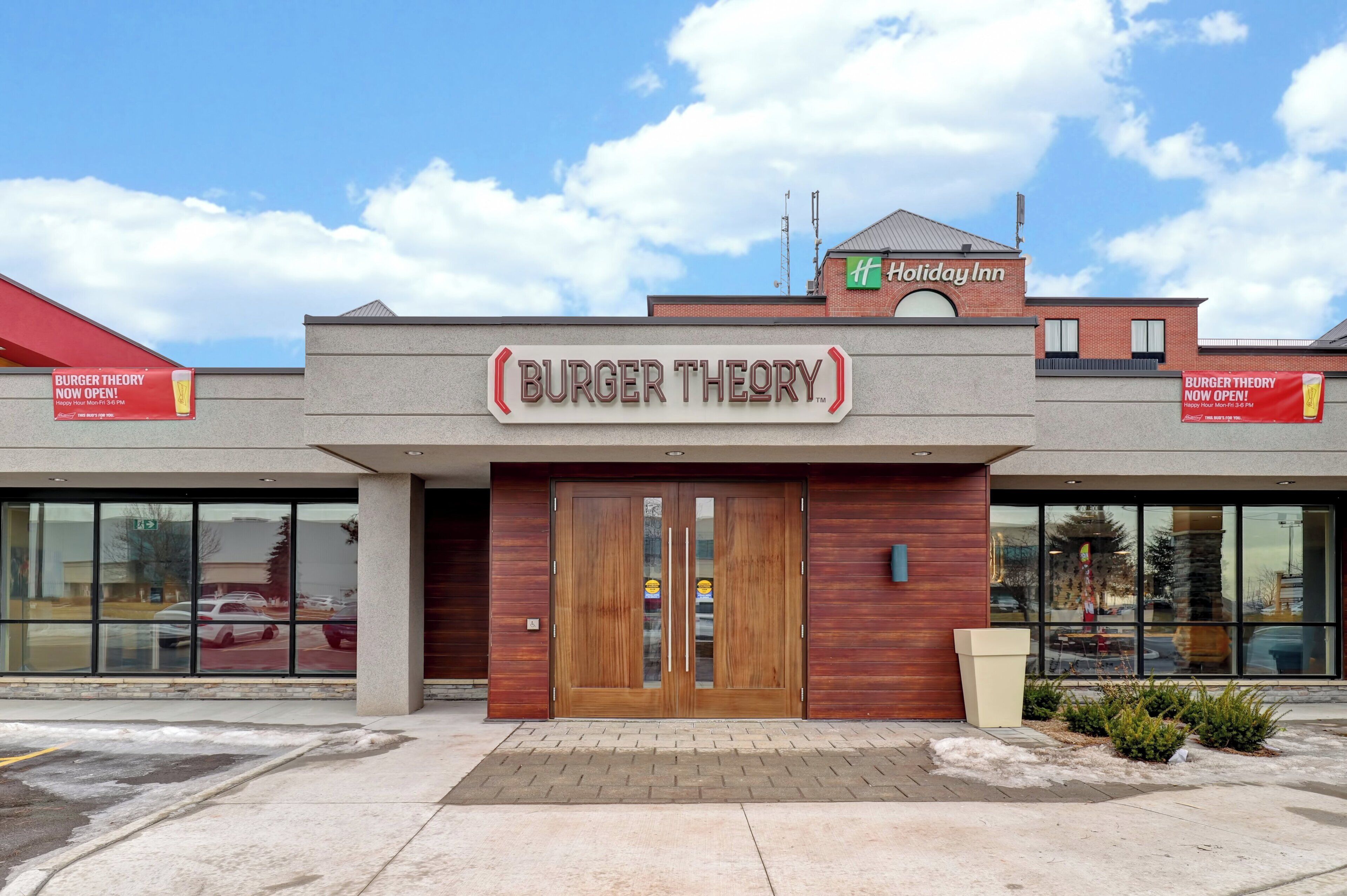 A Burger Theory restaurant with a Holiday Inn sign above it.