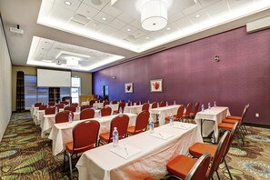 A conference room with tables and chairs, a projector, and a presentation screen.