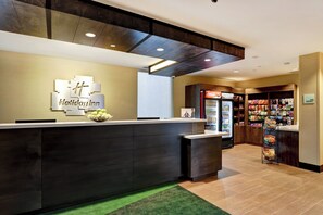A hotel reception area with a modern design, a reception desk, and a Coca-Cola refrigerator. - Holiday Inn Mississauga Toronto West by IHG (Mississauga)