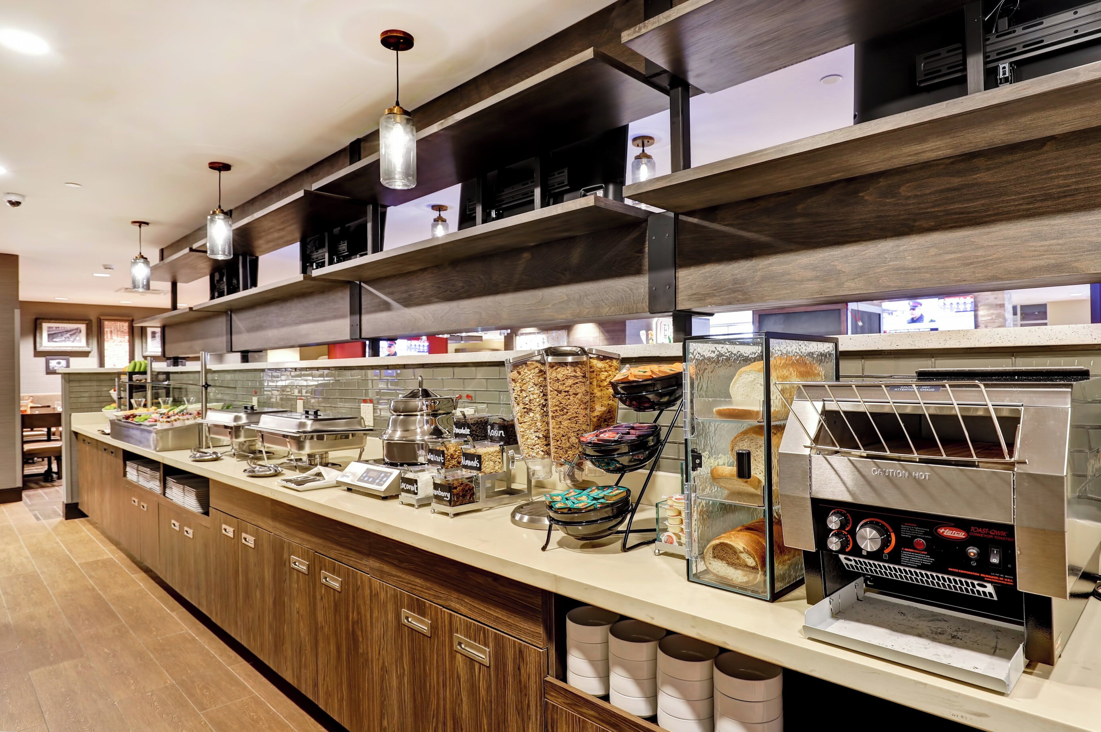A self-service breakfast station with various food options, a coffee machine, and a toaster oven.
