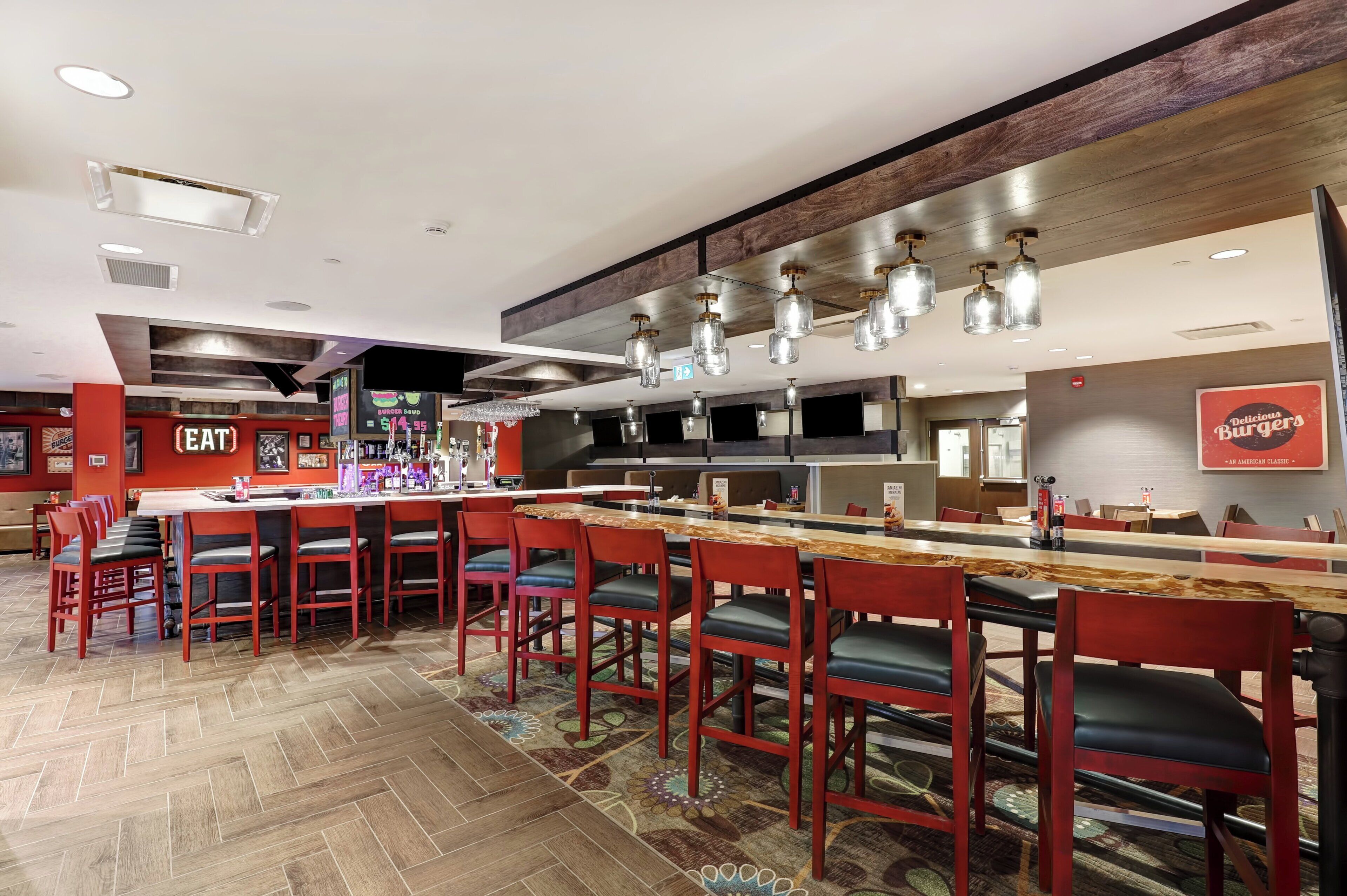 Um restaurante com área de bar, diversas opções de assentos e design de interiores moderno.