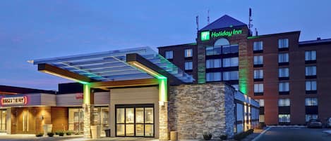 A Holiday Inn hotel with a glass entrance canopy, a brick building, and a visible sign for Burger Theory.
