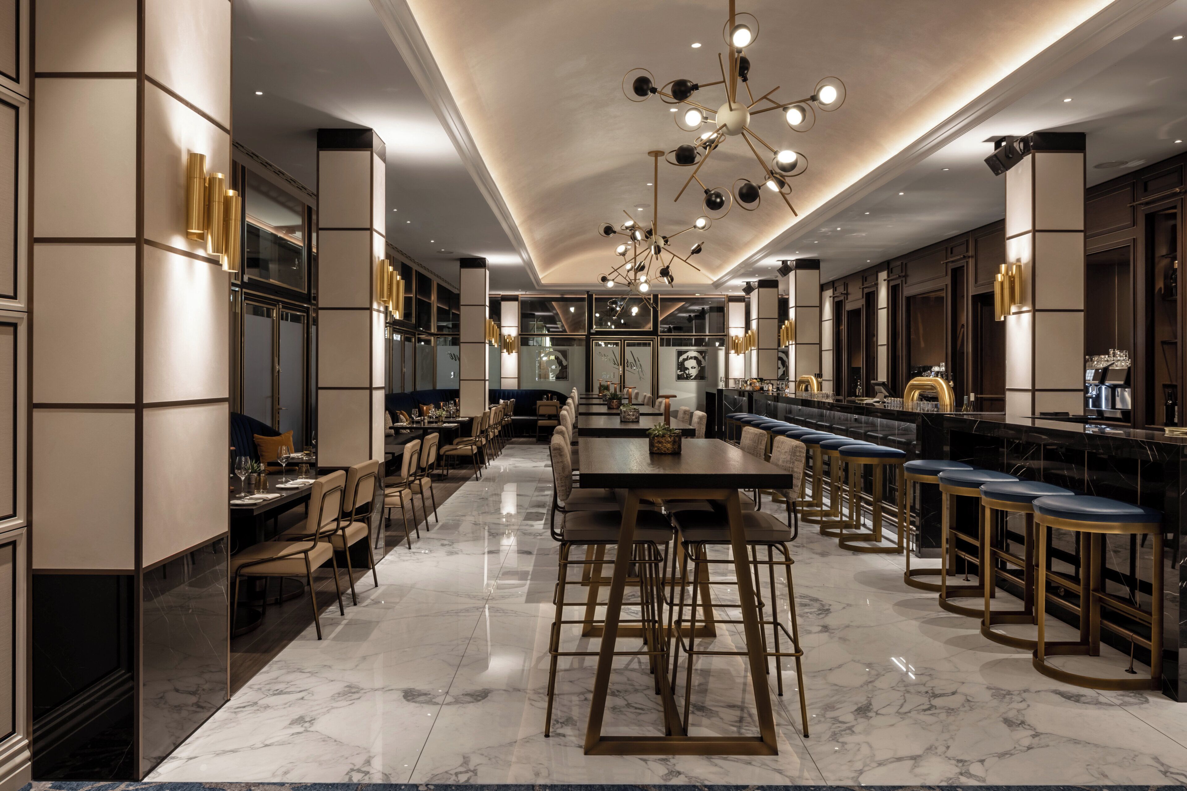 A modern hotel lobby with a long reception desk, bar area, and seating.