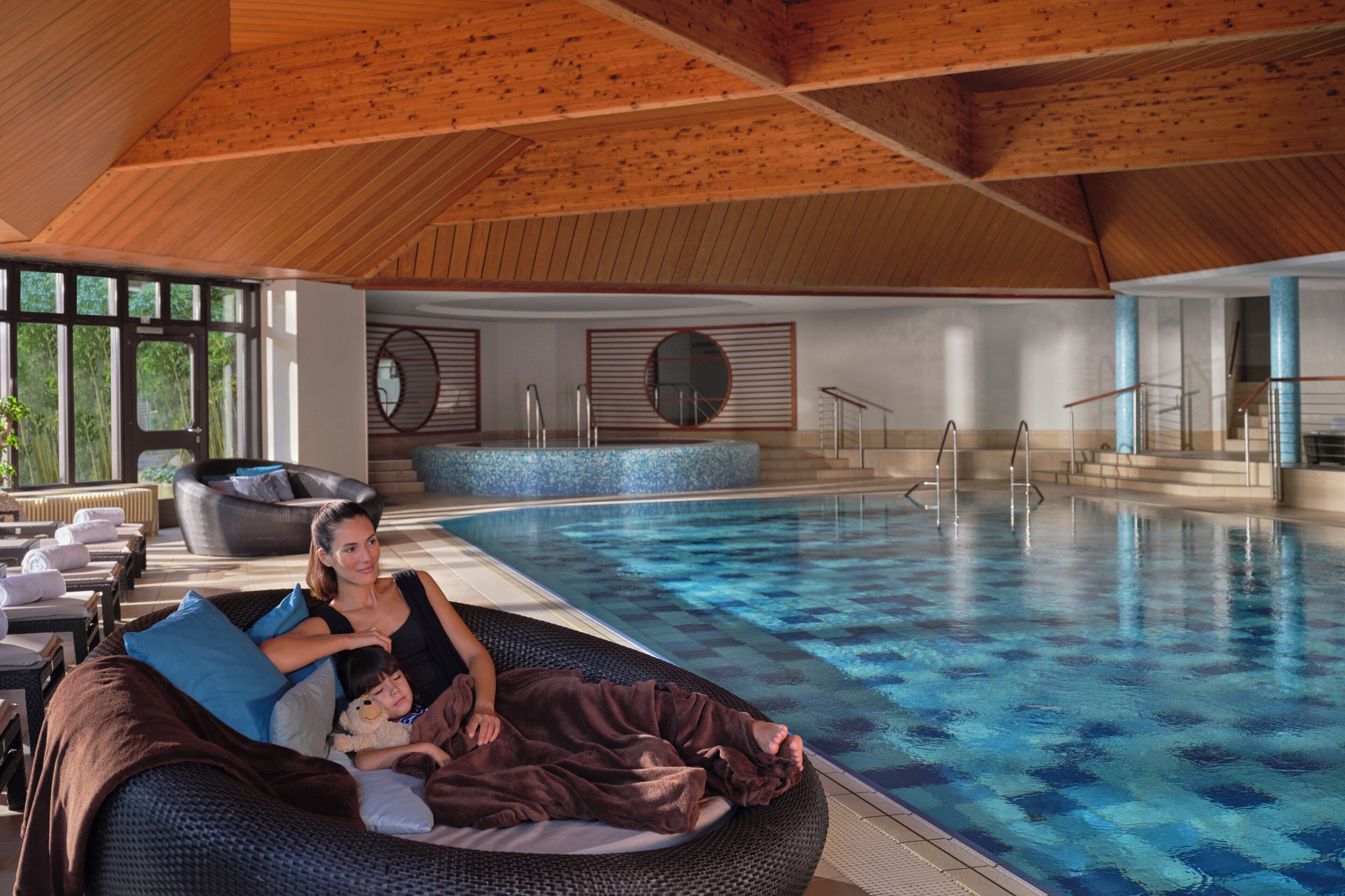 Ein Poolbereich mit Liegestuhl, einer Sitzbank und einer sitzenden Person.