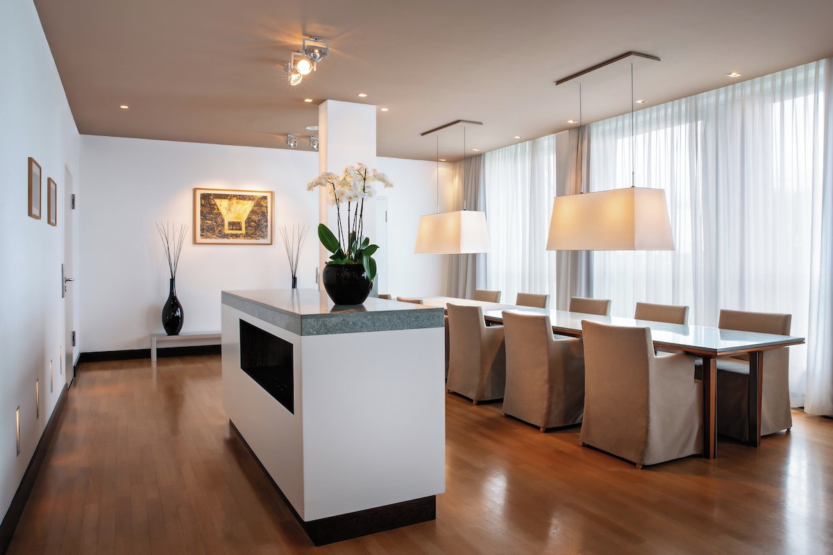 Un comedor moderno con una isla central, un jarrón con flores y una mesa de comedor con sillas.