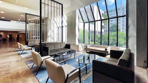 Un vestíbulo espacioso con mobiliario moderno, ventanas amplias que ofrecen vistas de la ciudad y un llamativo separador decorativo en blanco y negro.