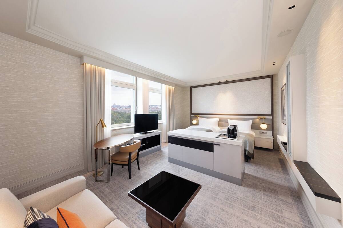Moderni hotellihuone, jossa on työpöytä, sänky, televisio ja näkymä kaupunkiin.