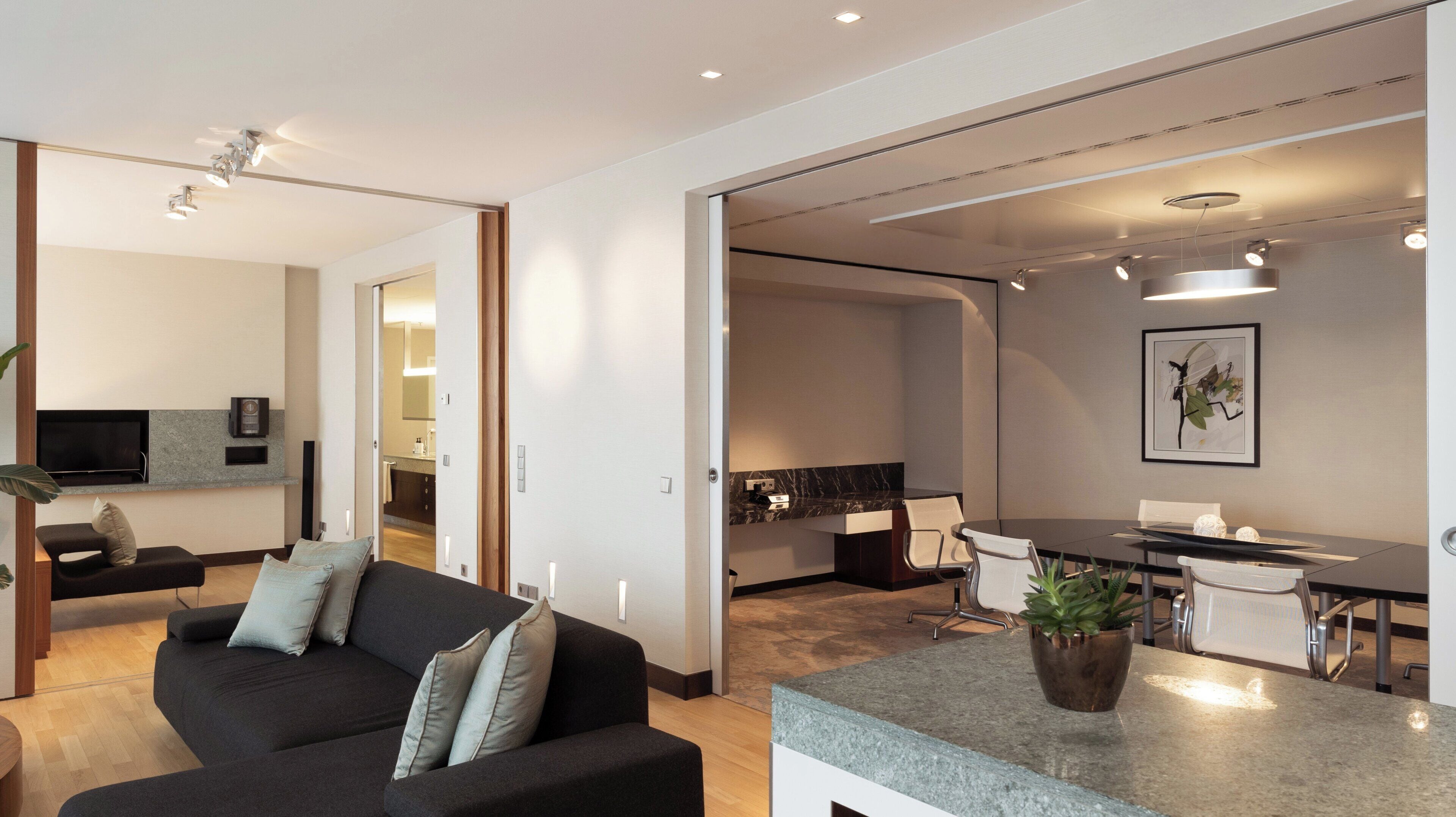 Una sala de estar moderna con un sofá, un televisor y una zona de comedor con mesa y sillas.