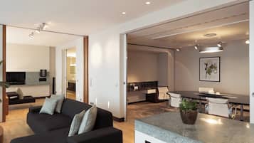 Una sala de estar moderna con un sofá, un televisor y una zona de comedor con mesa y sillas.