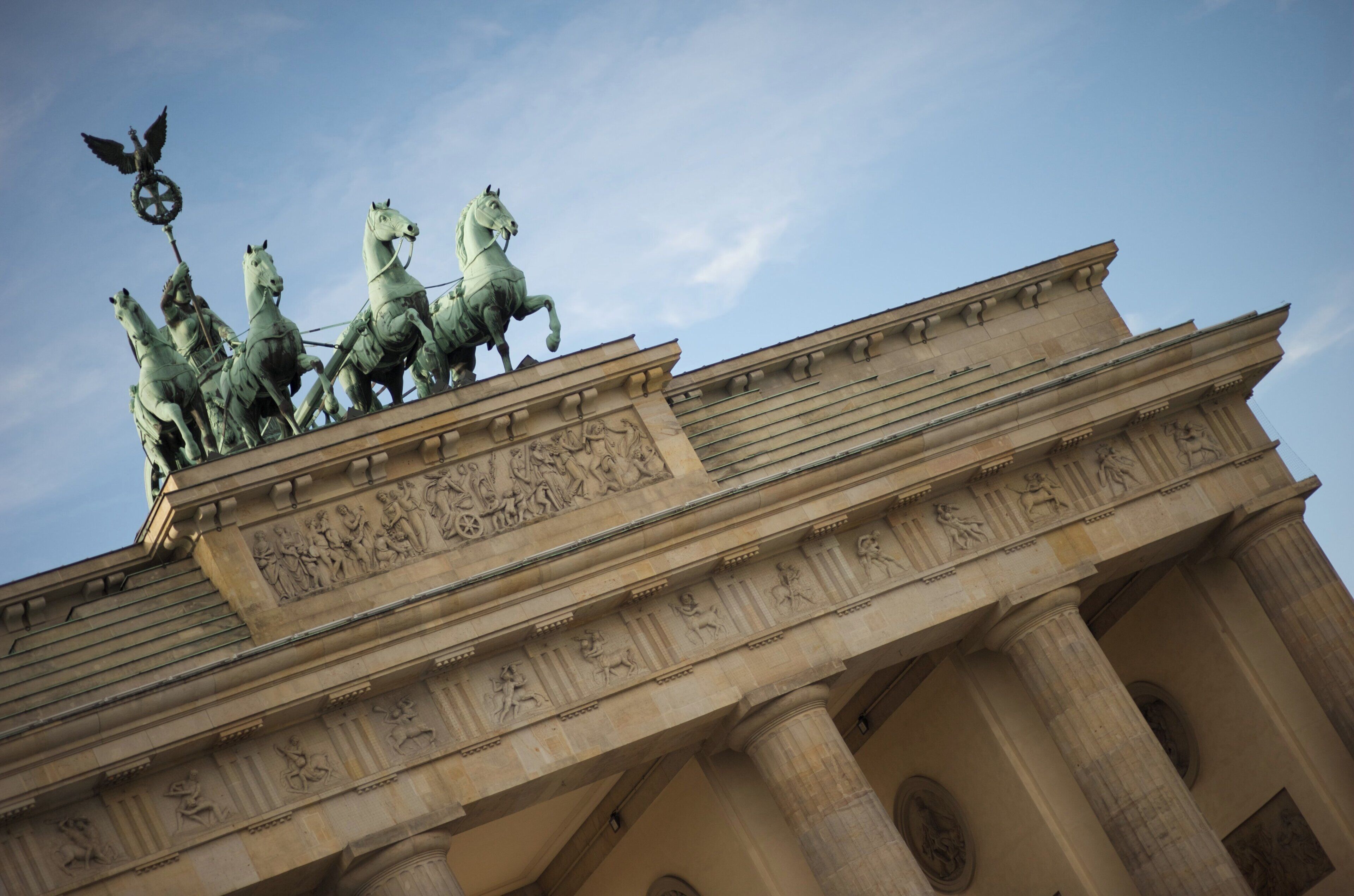 A large, classical building with a prominent sculpture of horses and riders on top.