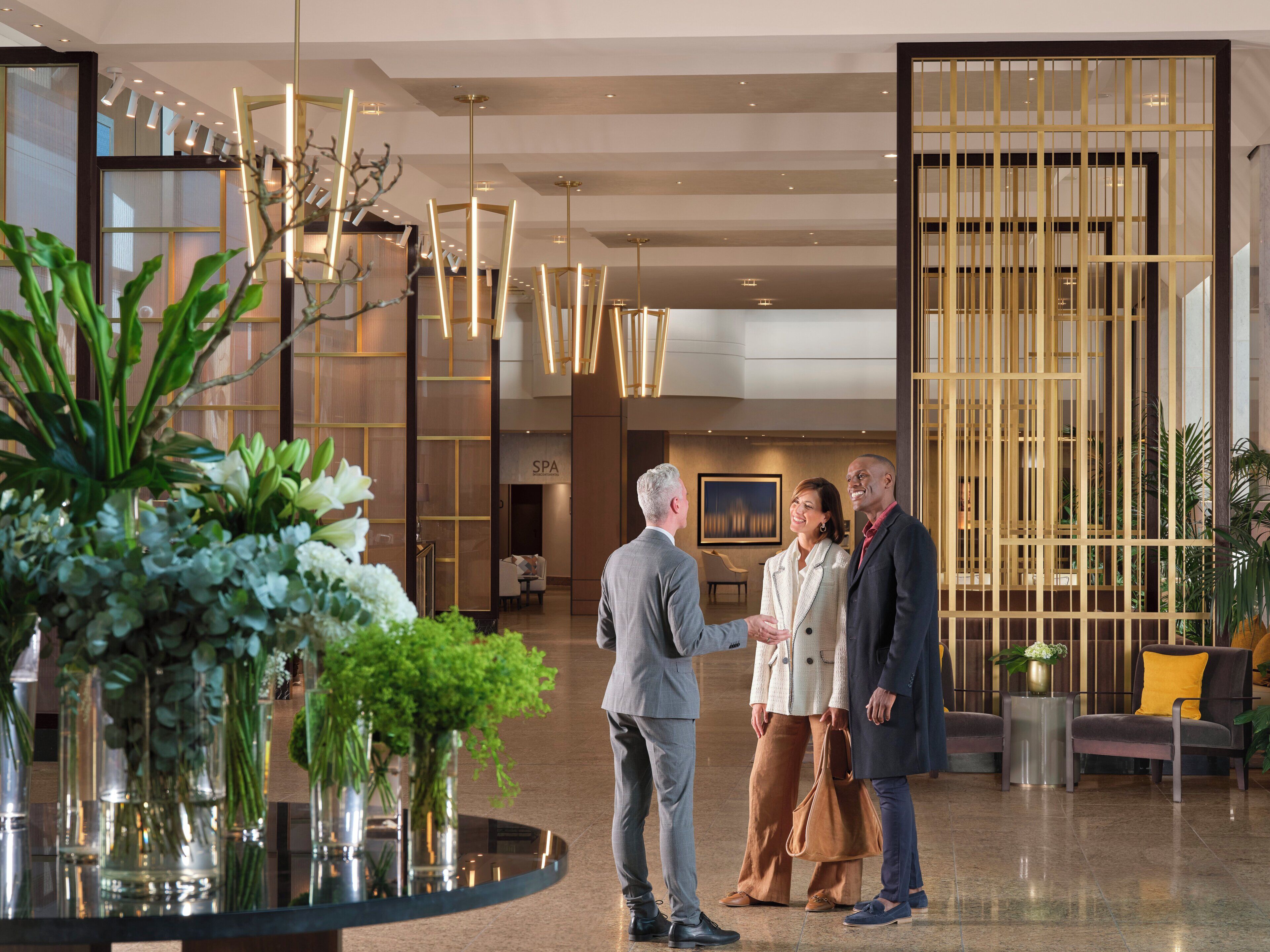 A modern lobby with a reception desk, a spa sign, and a decorative plant arrangement.
