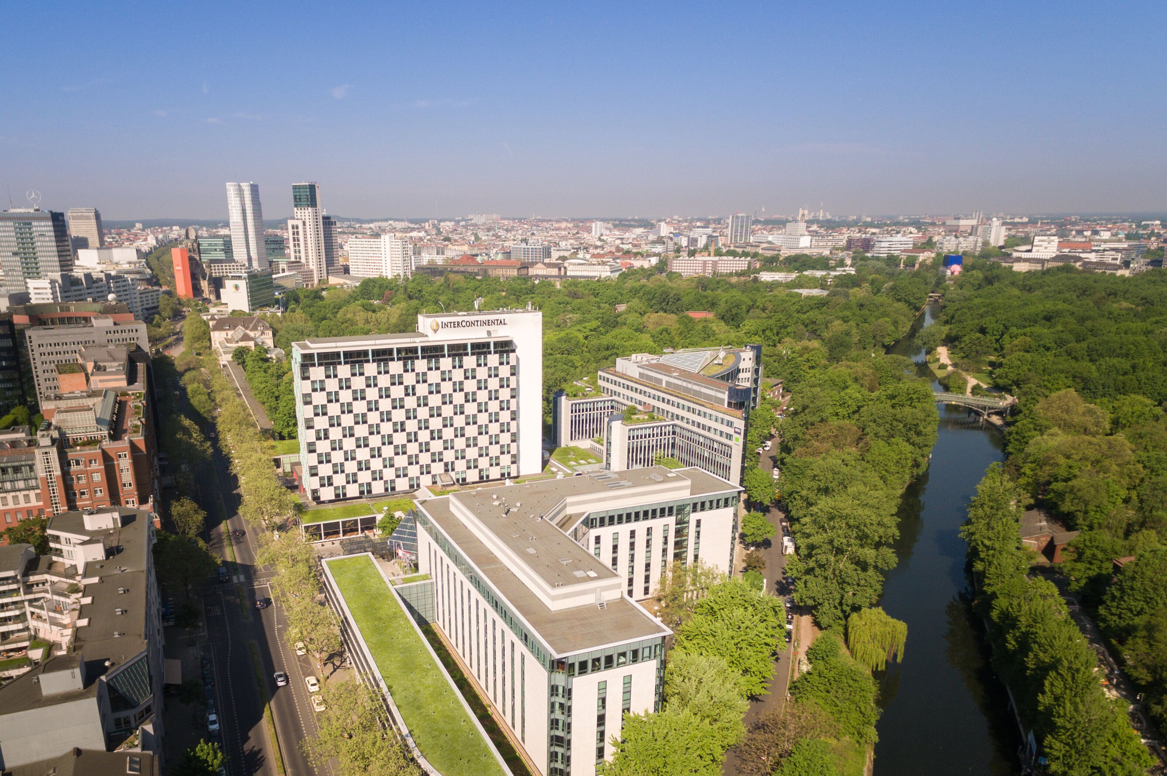 Ein moderner Gebäudekomplex mit einem markanten InterContinental Hotel, umgeben von üppiger Vegetation und einem Fluss.