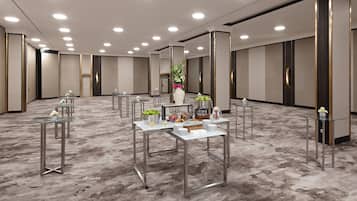 A spacious conference room with multiple tables, a large vase with flowers, and a carpeted floor.