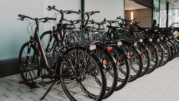 Rivi polkupyöriä on pysäköity sisätilaan, jossa on laatoitettu lattia ja seinässä on kyltti.