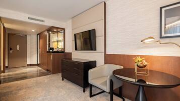 A hotel room with a desk, chair, TV, and a mirror.
