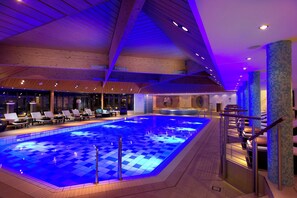 An indoor swimming pool with a checkered floor, lounge chairs, and a staircase with a glass barrier. - InterContinental Berlin by IHG (Berlin)