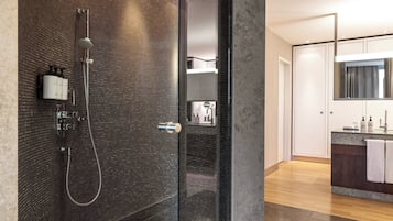 Ein modernes Badezimmer mit einer Duschkabine, einem Waschtisch mit Spiegel und Holzboden.