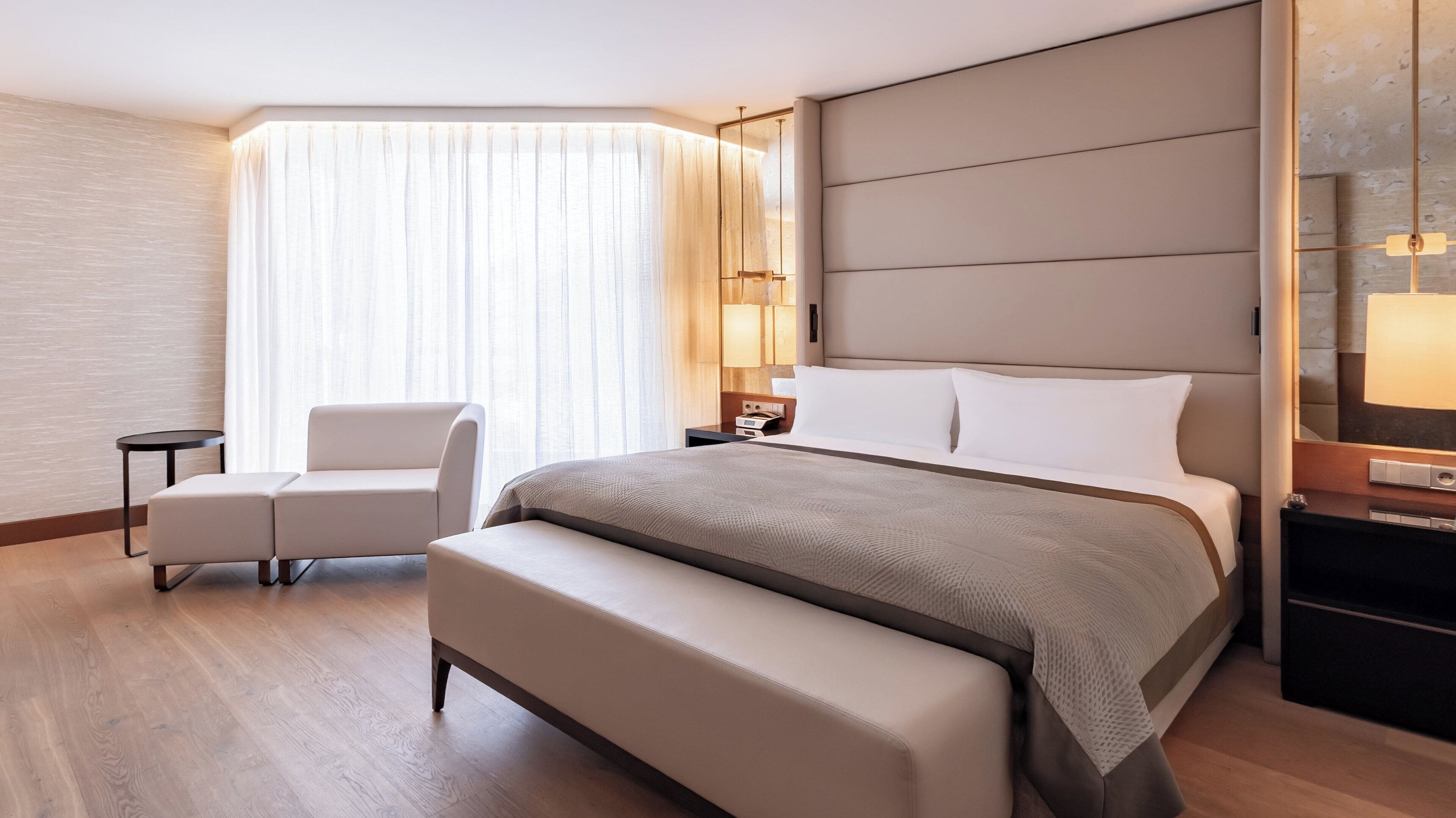 Ein modernes Hotelzimmer mit einem großen Bett, einem Nachttisch, einem Stuhl und einem kleinen Tisch.